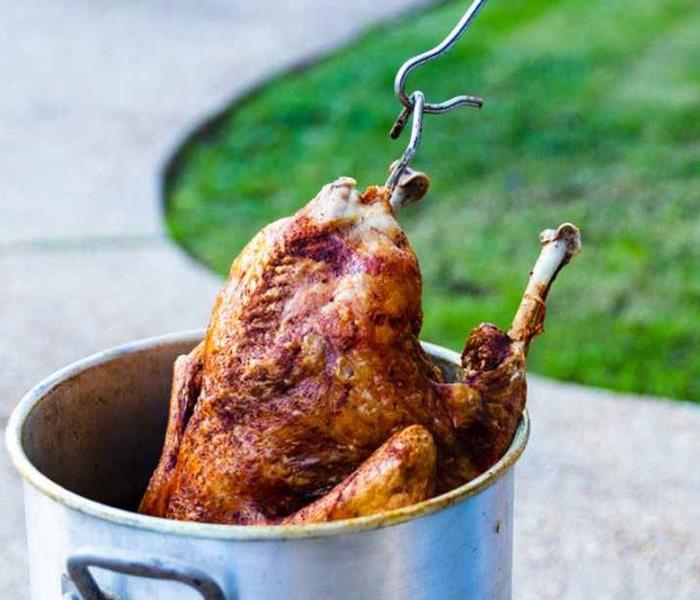 A turkey being lowered into a deep fryer