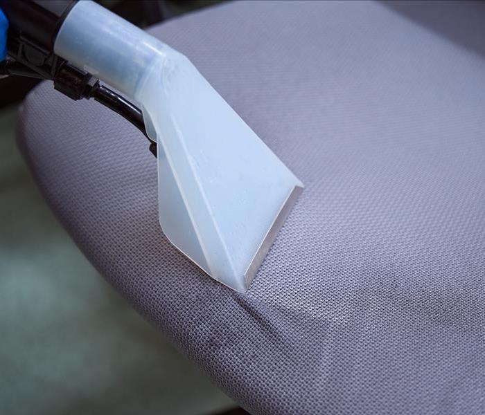 Close-up photo of upholstery vacuum-cleaner nozzle being used on top of a chair