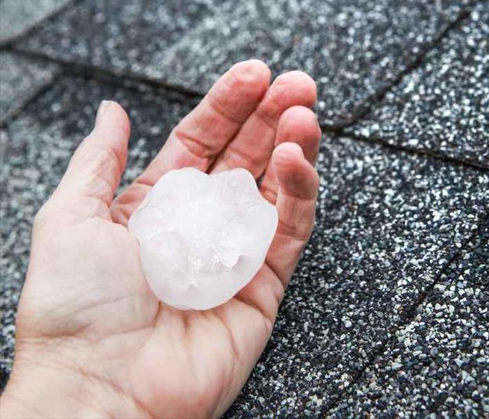 A person holding a hailstone near a roof
